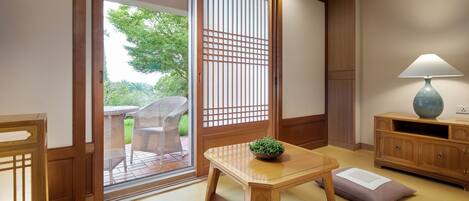 A traditional Japanese room with tatami flooring, a sliding door, a table with a plant, and a lamp.