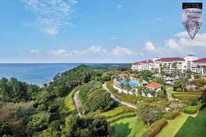 A resort with a large building, a swimming pool, and a view of the ocean. - The Shilla Jeju (Seogwipo)