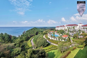 Un resort con un edificio grande, una piscina y vista al océano.