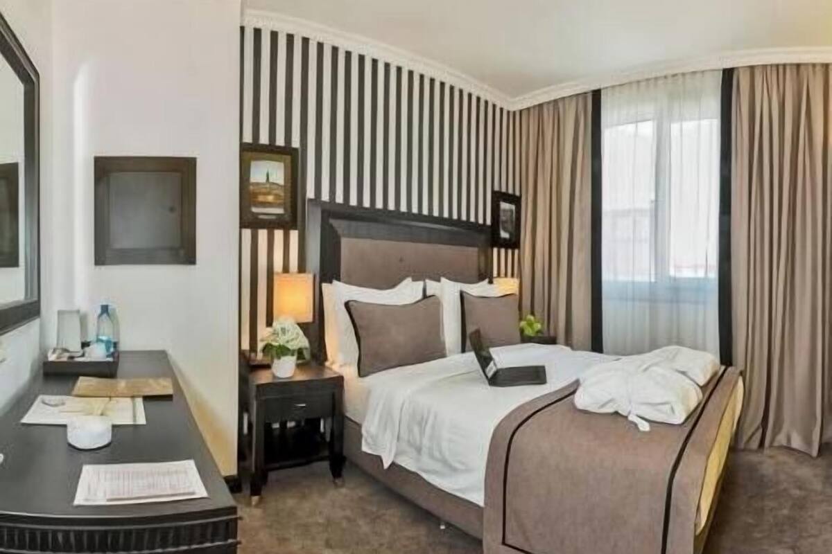 Une chambre d’hôtel avec un lit, une table de chevet, une lampe et un miroir.