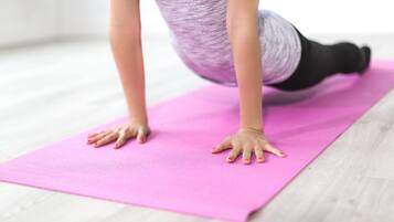 A person performing a yoga pose on a pink exercise mat.