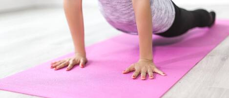 Una persona realizando una postura de yoga sobre una colchoneta rosa.