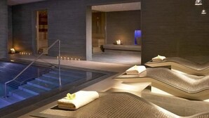 A modern spa area with a pool, seating areas, and a staircase leading to a private room. - The Maryborough Hotel and Spa (Douglas)