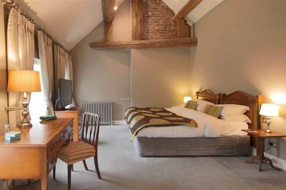 Een slaapkamer met een bed, nachtkastjes, een bureau en een stoel.
