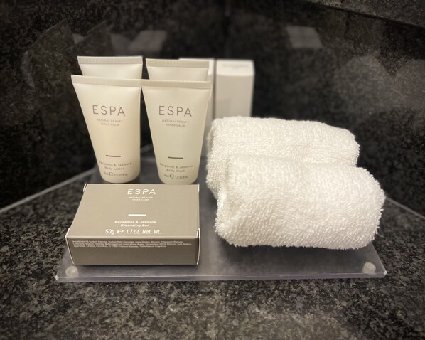 A display of ESPA natural beauty products, including body wash and cleansing bar, on a granite countertop.