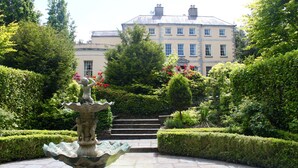 A well-maintained garden with a central fountain, trimmed hedges, and a large building in the background. - The Maryborough Hotel and Spa (Douglas)