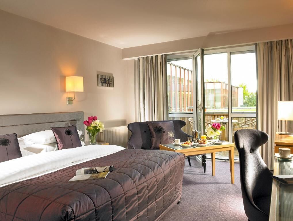 Una habitación de hotel con cama, escritorio, silla y vistas al exterior.