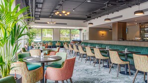 A restaurant with green booths, colorful chairs, and a bar area. - The Plaza Hotel (Dublin)