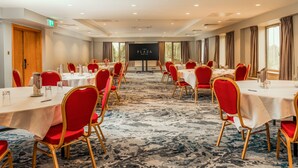 A conference room with tables and chairs, a projection screen, and a view of the outdoors. - The Plaza Hotel (Dublin)