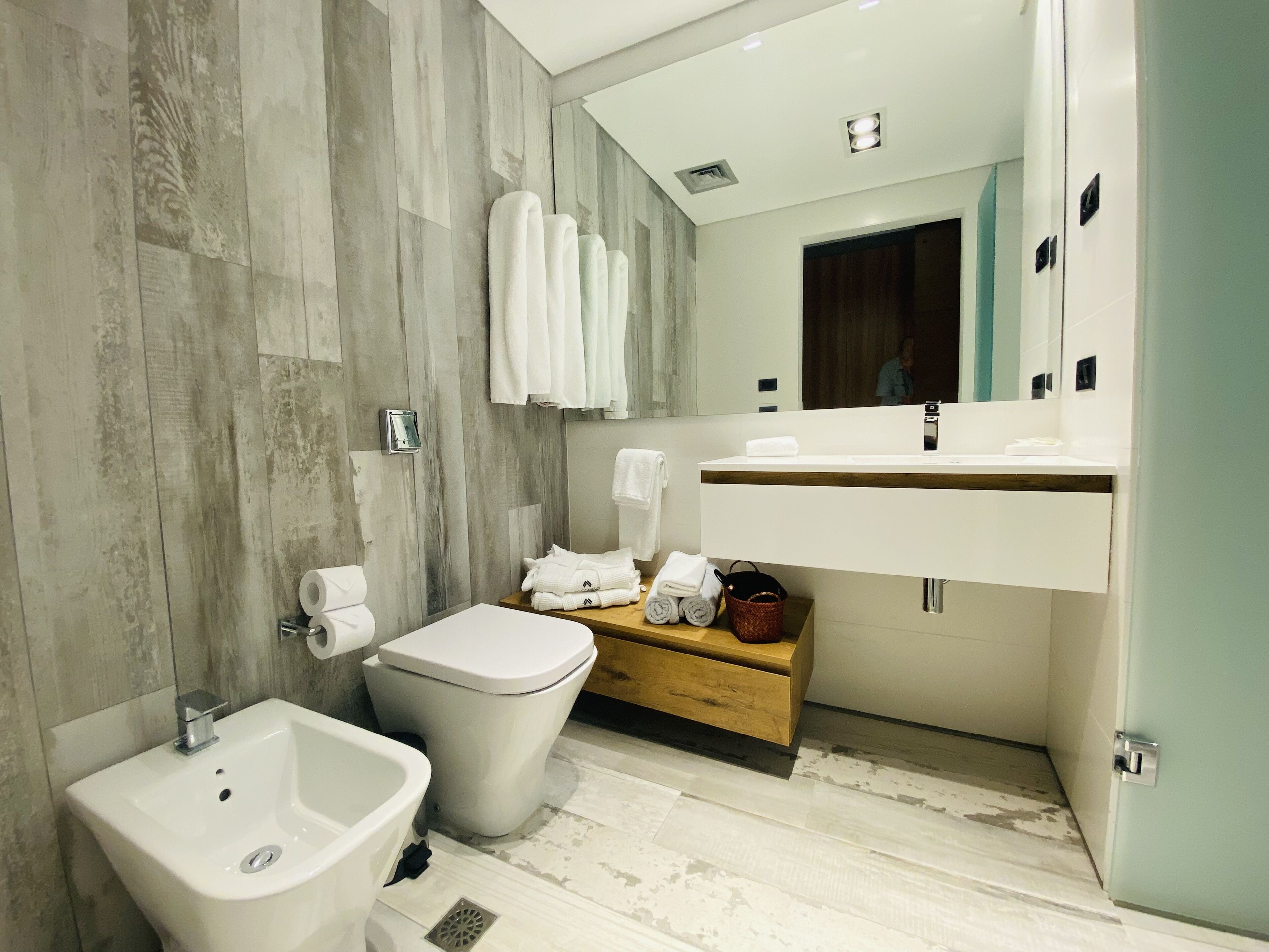 A modern bathroom with a bidet, toilet, and vanity with a mirror.