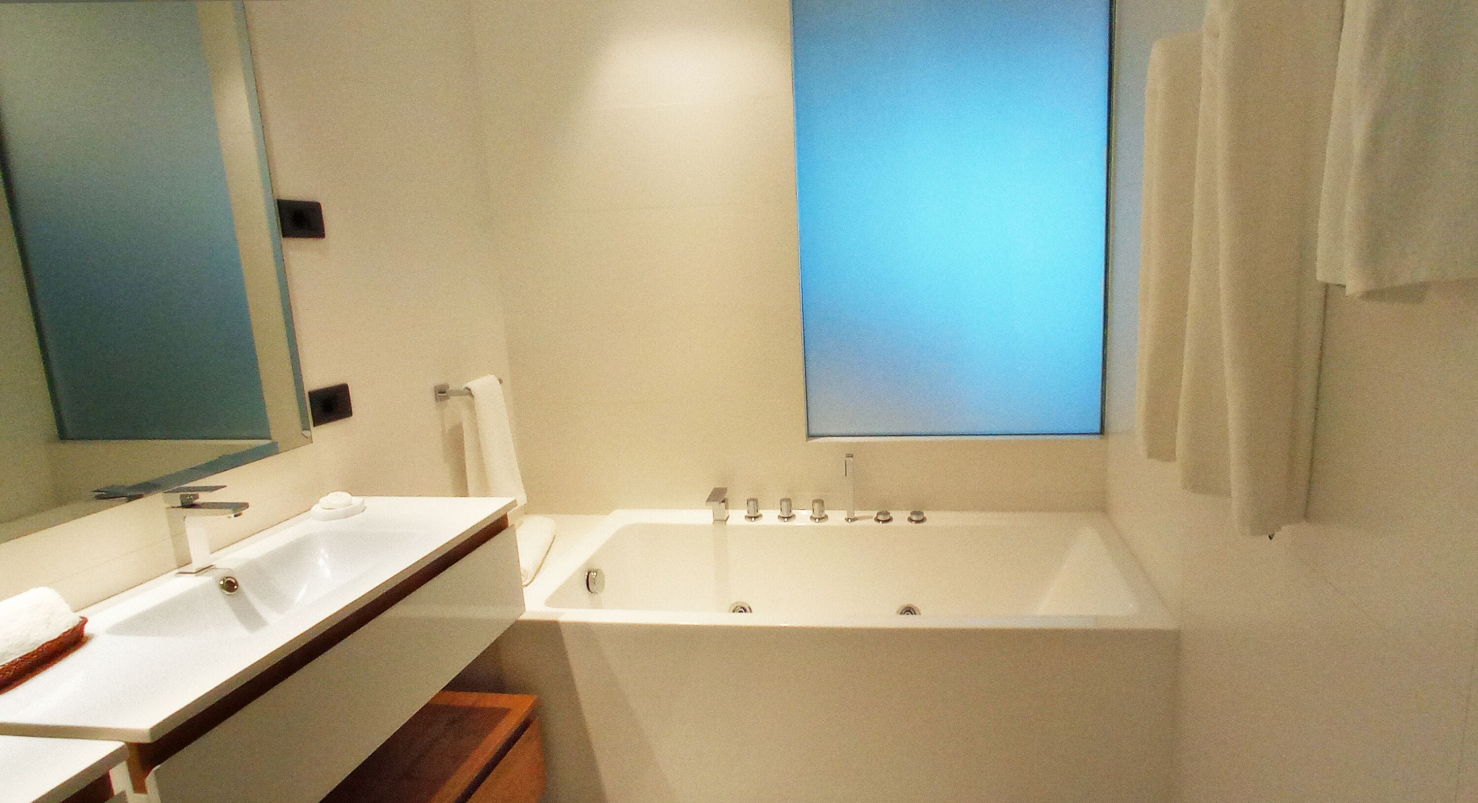 Un baño moderno con lavamanos doble, bañera y un espejo grande.