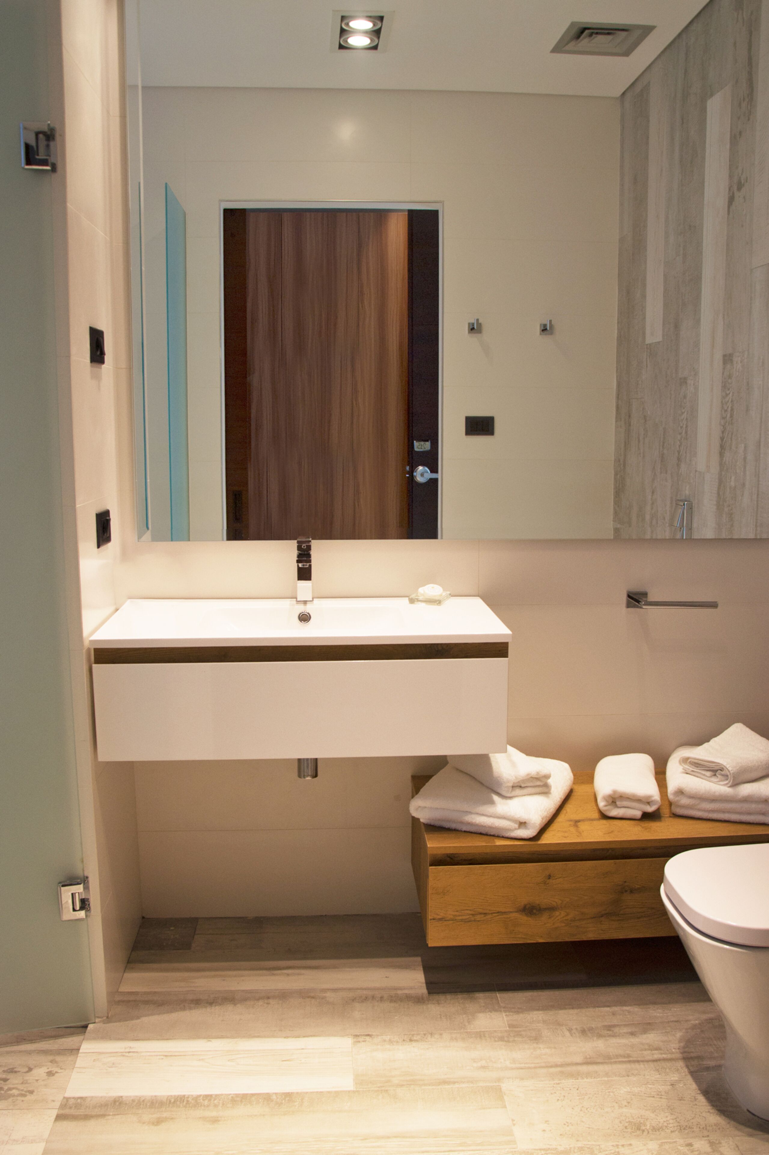 A modern bathroom with a white sink, wooden vanity, and a toilet.