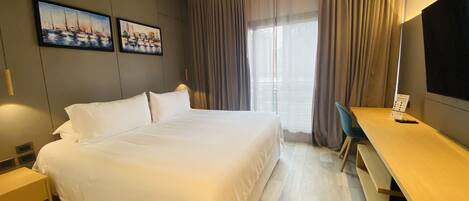 Una habitación de hotel con una cama grande, un escritorio y una televisión.