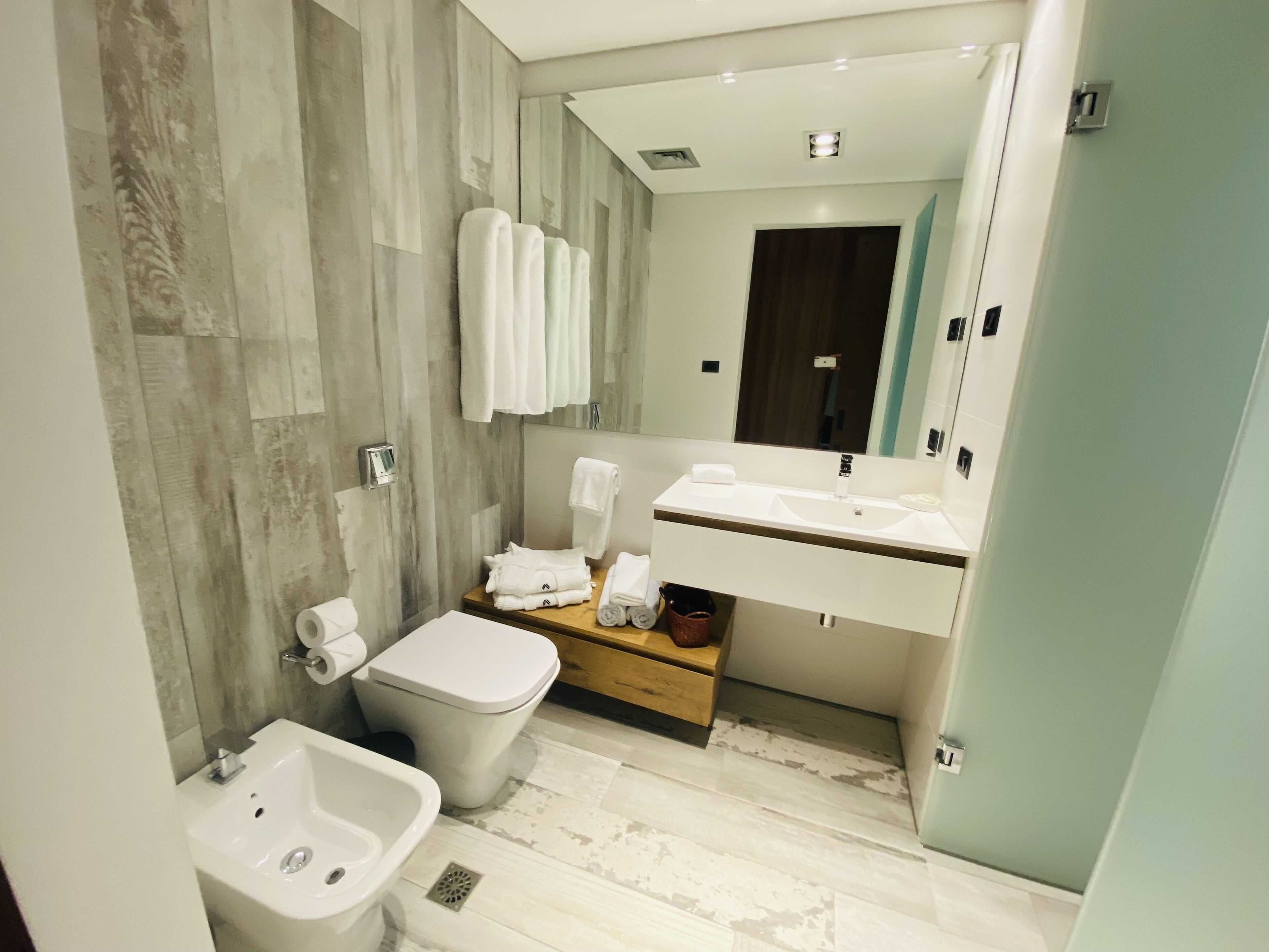 A modern bathroom with a bidet, a toilet, a sink, and a mirror.