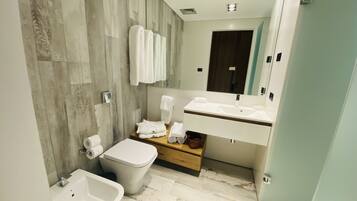 A modern bathroom with a bidet, a toilet, a sink, and a mirror.