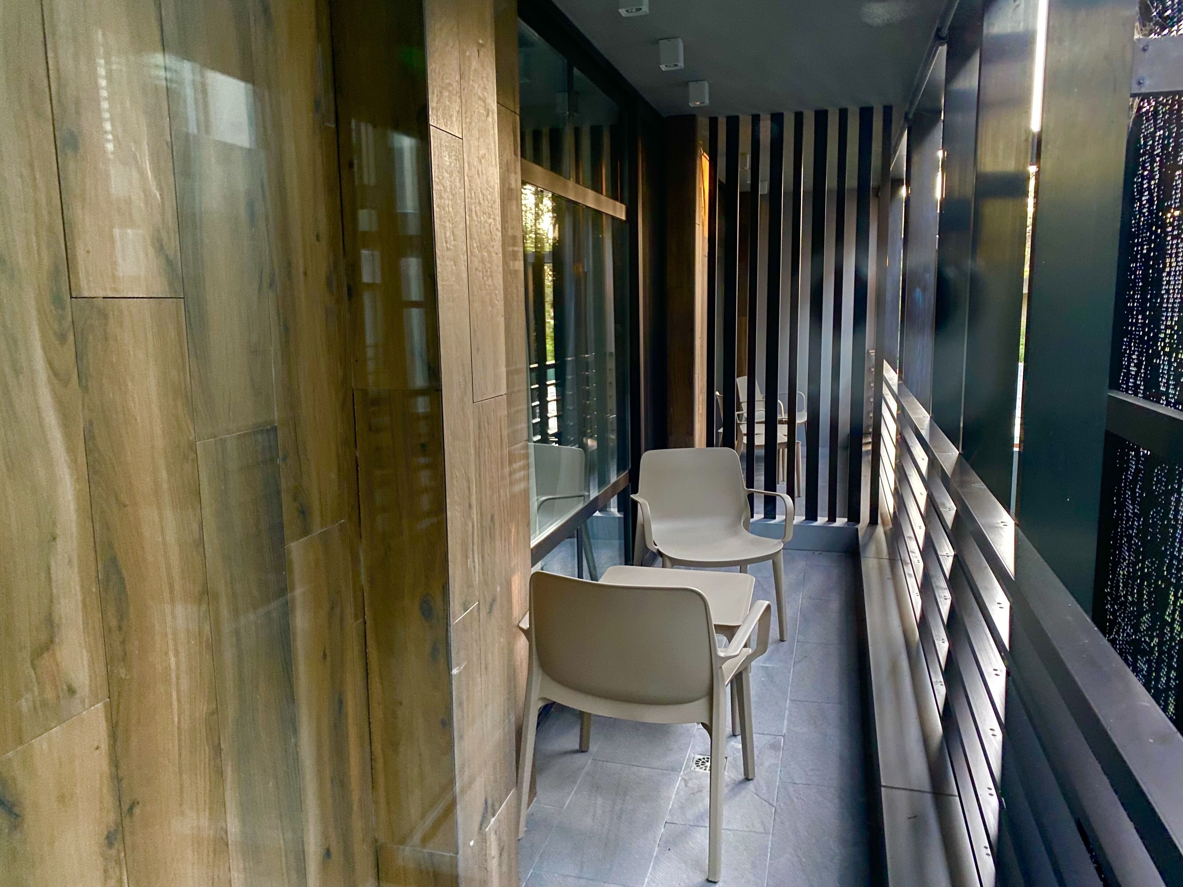 A modern interior with a glass partition, two white chairs, and a small table.