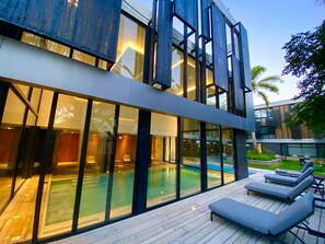 A modern building with a large swimming pool, glass walls, and outdoor seating. - Hotel La Capilla (Punta del Este)