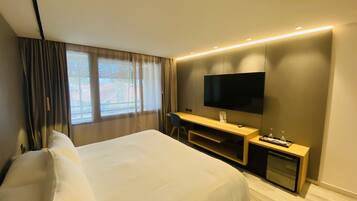 A hotel room with a bed, a desk, a TV, and a window with curtains.