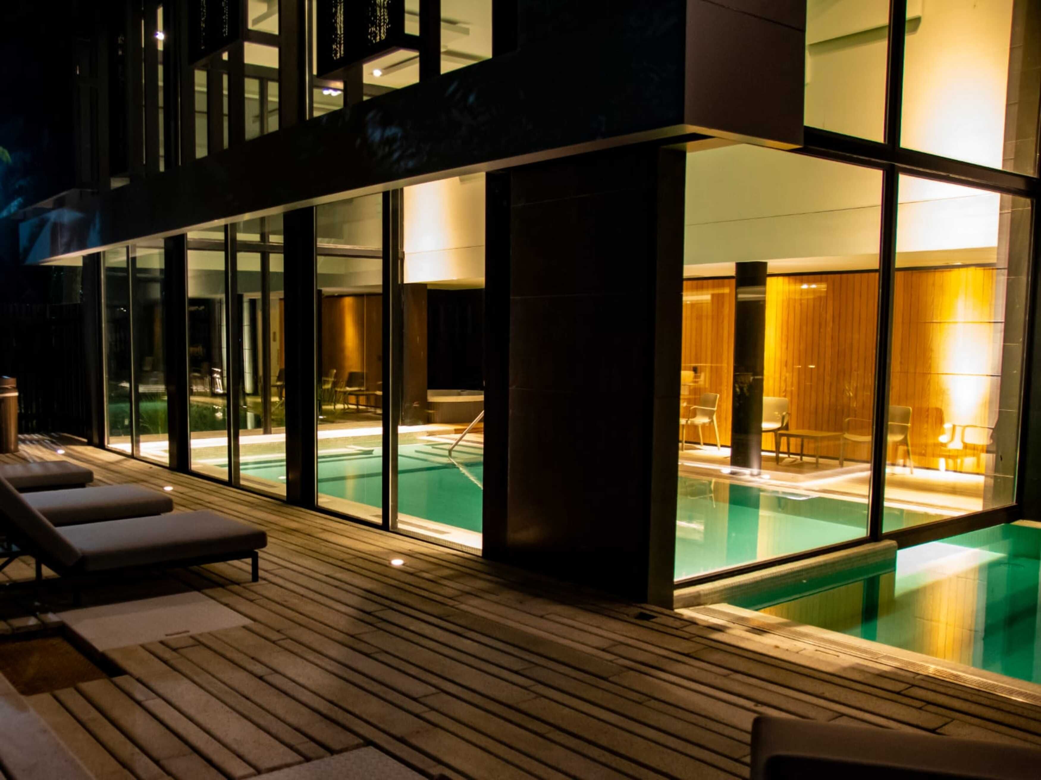 A modern hotel with a pool area, including lounge chairs and a wooden deck.