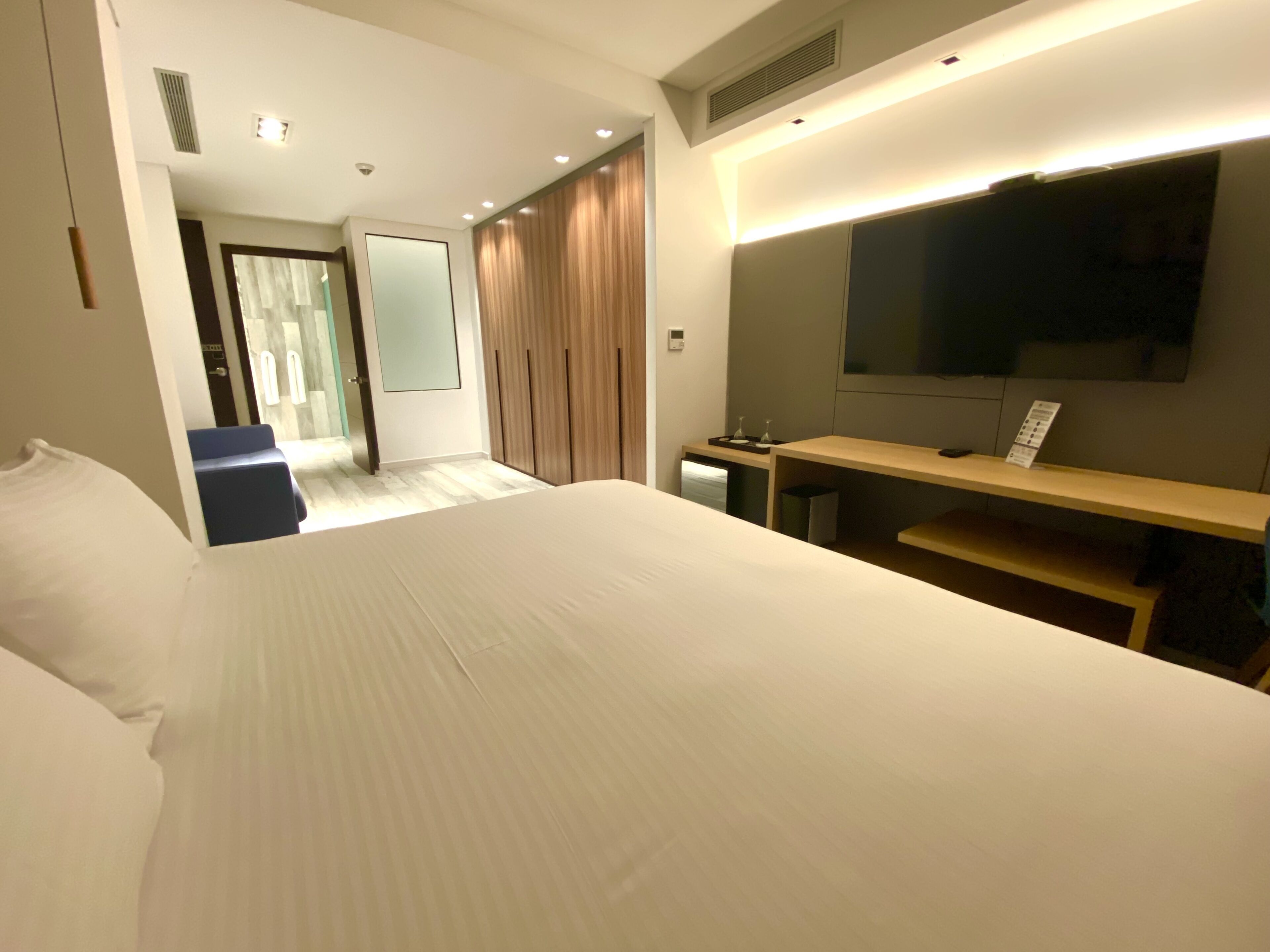 Una habitación de hotel moderna con una cama grande, televisión, escritorio y espejo.