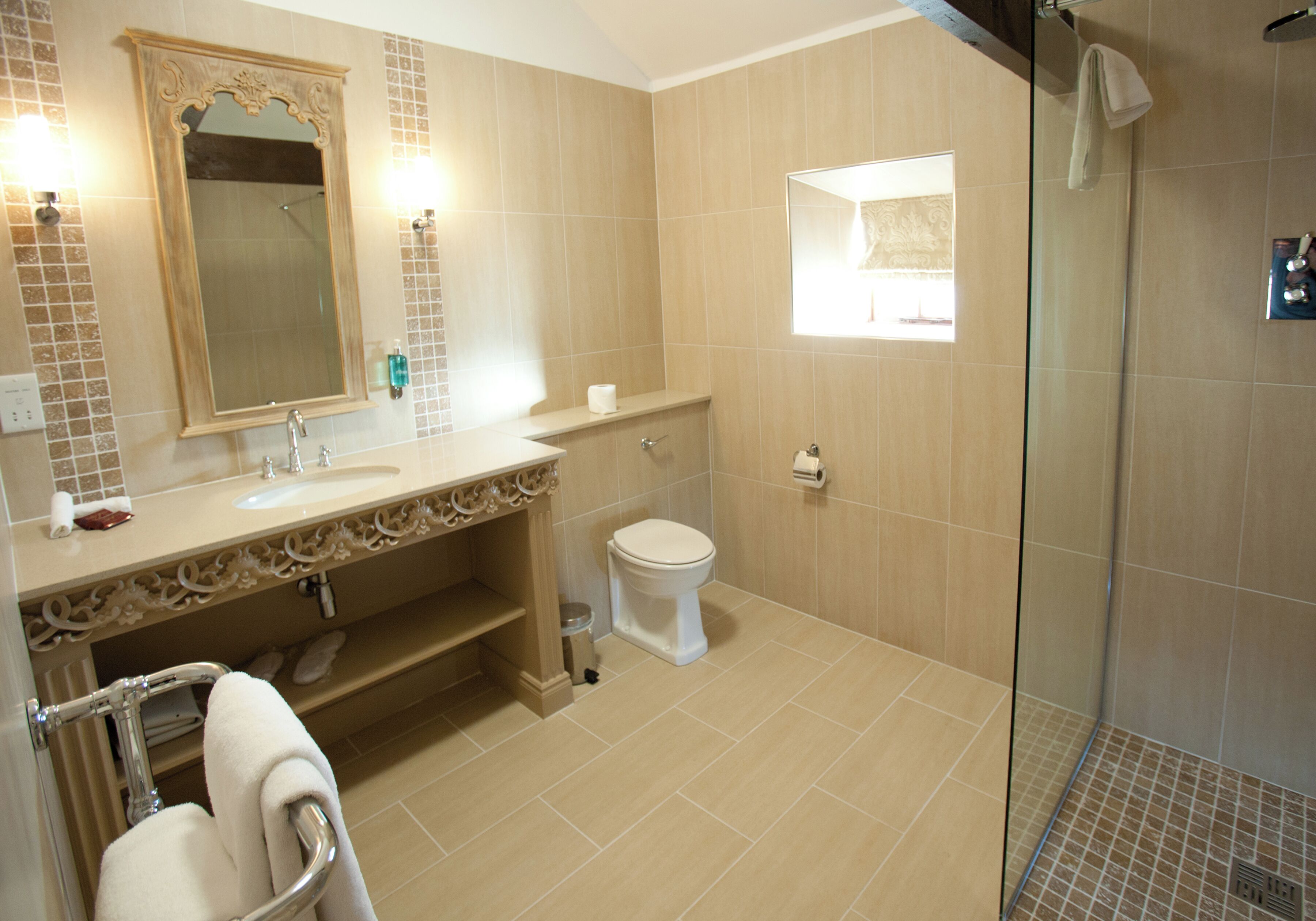 A bathroom with a sink, mirror, toilet, and shower area.