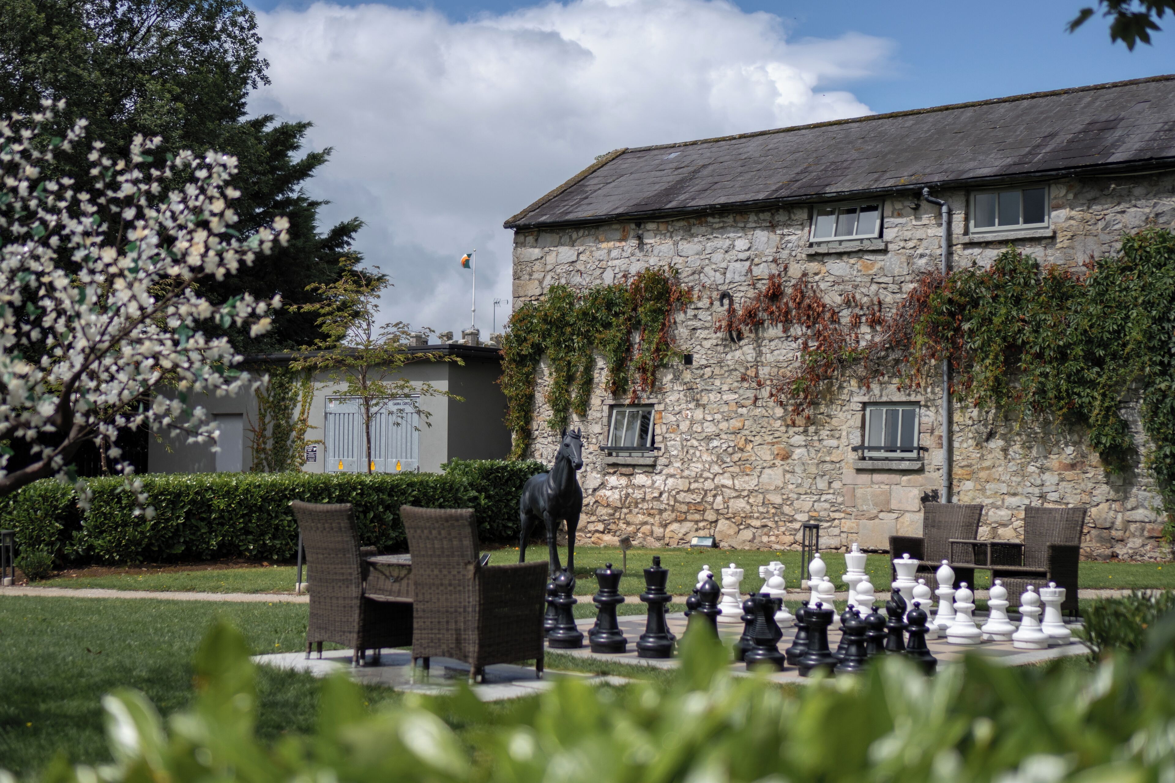 A stone building with ivy, outdoor seating, and a chessboard.