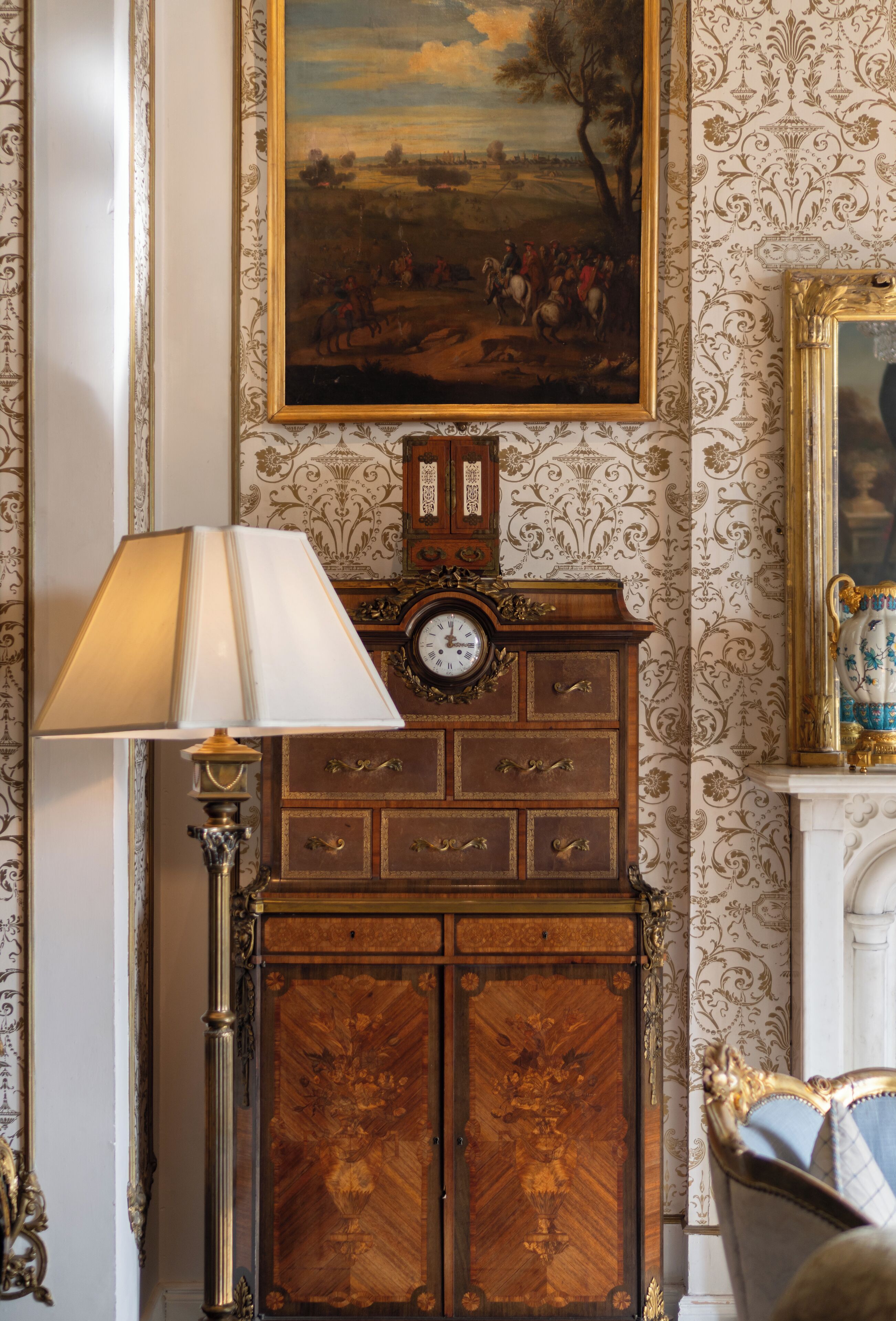 A room with a wooden cabinet, a clock, and a lamp.