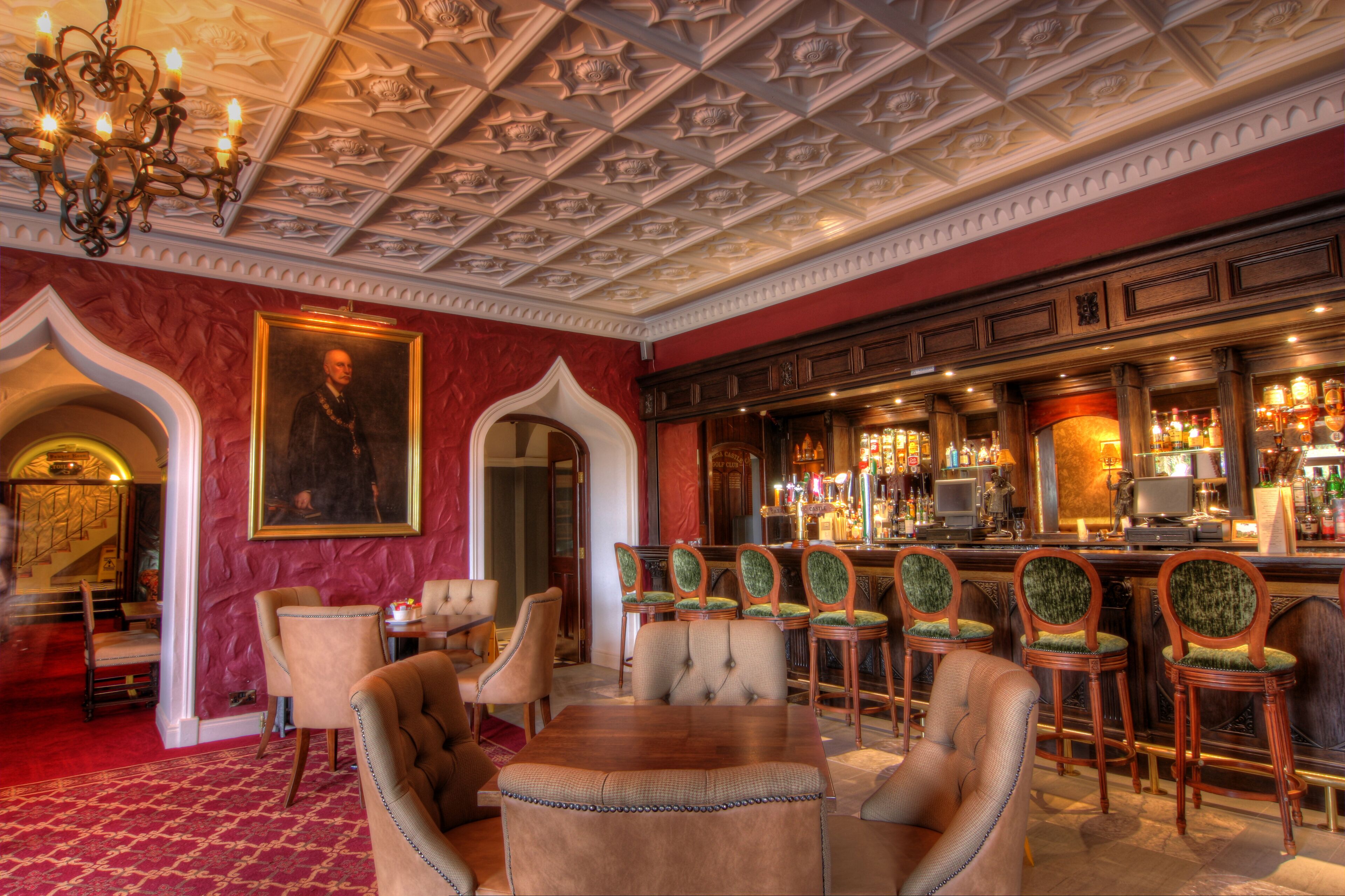 A bar area with wooden chairs, a bar counter, and a chandelier.