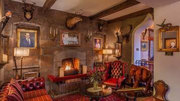 A traditional interior with a stone fireplace, leather furniture, and framed portraits.