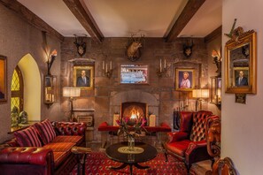 A traditional room with a fireplace, leather furniture, and mounted animal heads. - Cabra Castle Hotel (Kingscourt)