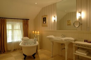 A classic bathroom with a freestanding bathtub, a pedestal sink, and a large mirror. - Cabra Castle Hotel (Kingscourt)