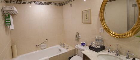 Une salle de bain avec une baignoire, des toilettes et deux lavabos.