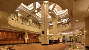 Un'ampia hall con un'area salotto centrale, diverse scale e un soffitto alto con lucernari.