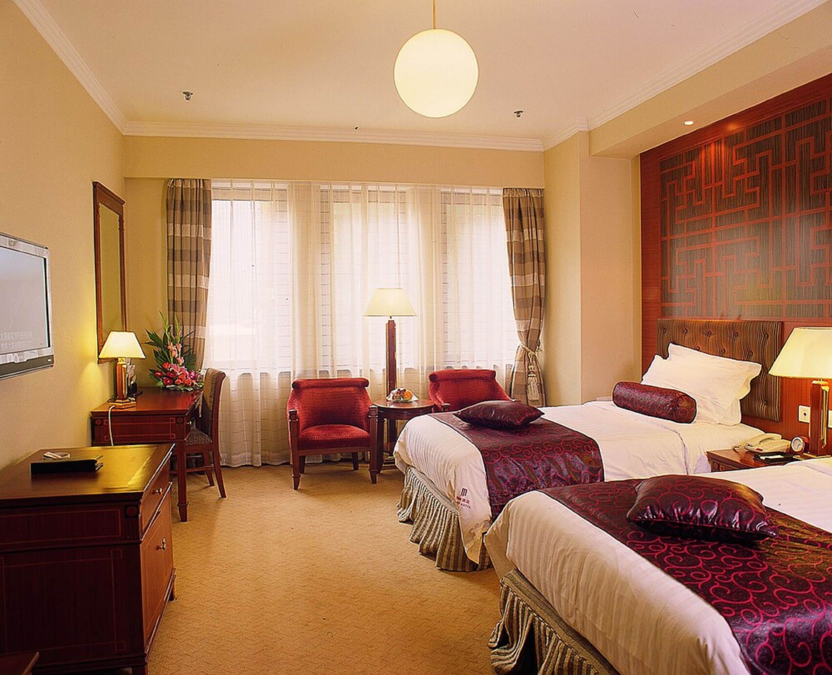 Een hotelkamer met een groot bed, een bureau, een stoel en een televisie.