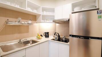 A modern kitchen with white cabinets, a stainless steel refrigerator, and a dish rack.