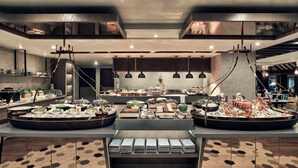 A modern restaurant with a central chef preparing food, surrounded by buffet-style food stations and dining areas. - Pan Pacific Hanoi (Hanoi)