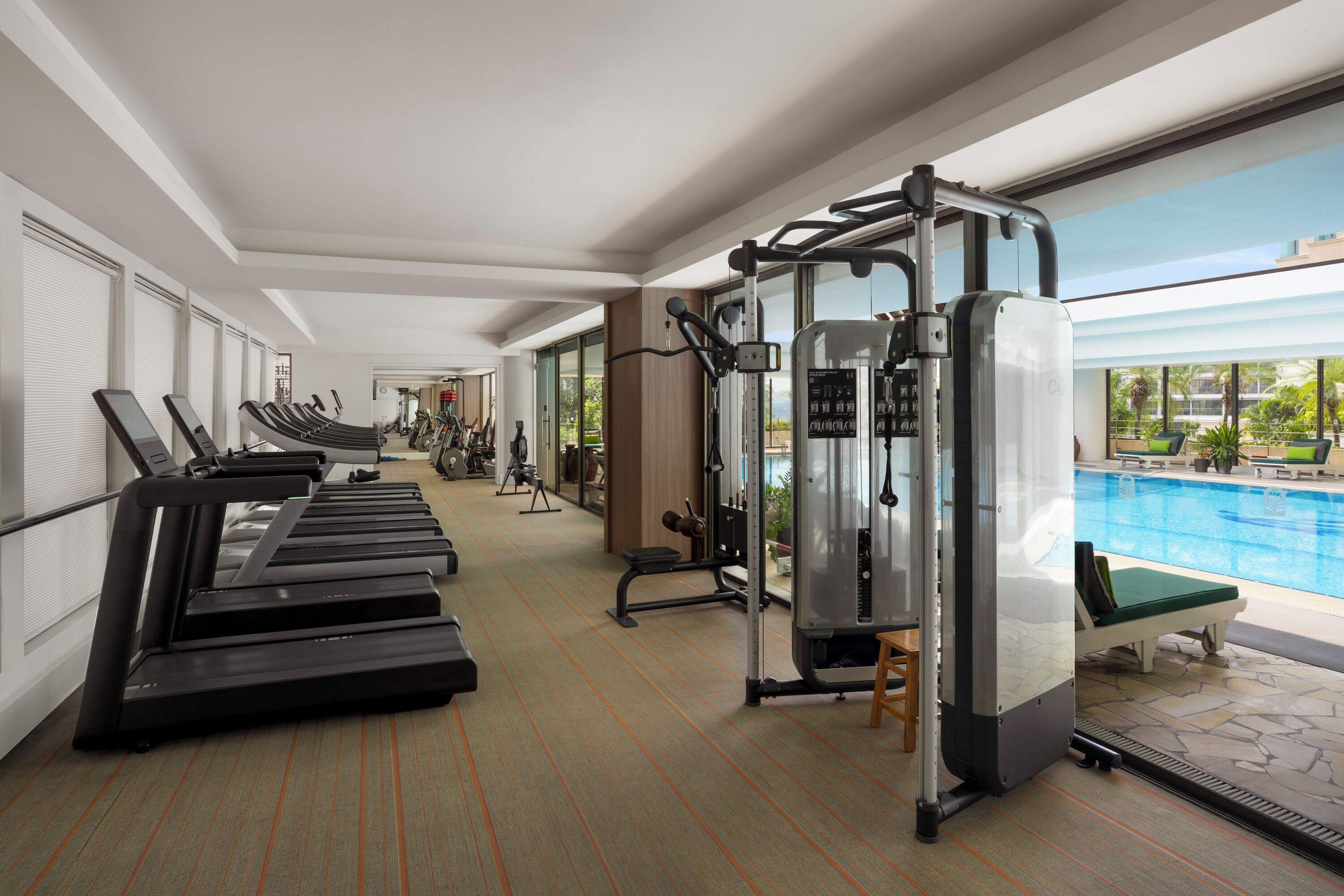 Un gimnasio con cintas de correr, máquinas de pesas y una zona de piscina.