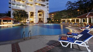 A hotel pool area with lounge chairs and a large building in the background. - Waterfront Suites Phuket by Centara (Karon)