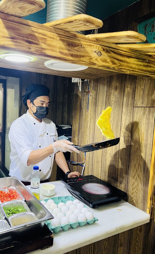A chef preparing food in a kitchen with wooden walls and a metal ceiling.