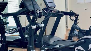 Ein Fitnessstudio mit Laufbändern, Crosstrainern und Kraftgeräten.