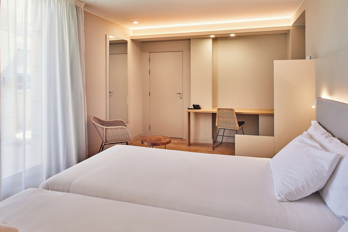 Une chambre d’hôtel moderne avec un grand lit, un bureau et une chaise.