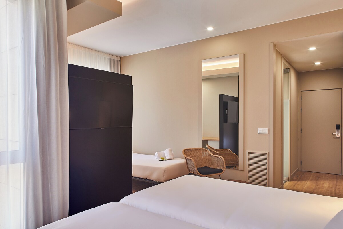 Une chambre d’hôtel avec deux lits, un grand miroir, une chaise et une armoire.