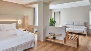 A modern hotel room with a large bed, a seating area with a sofa and a wooden coffee table, and a large mirror. - Hotel Silken Reino de Aragón (Zaragoza)