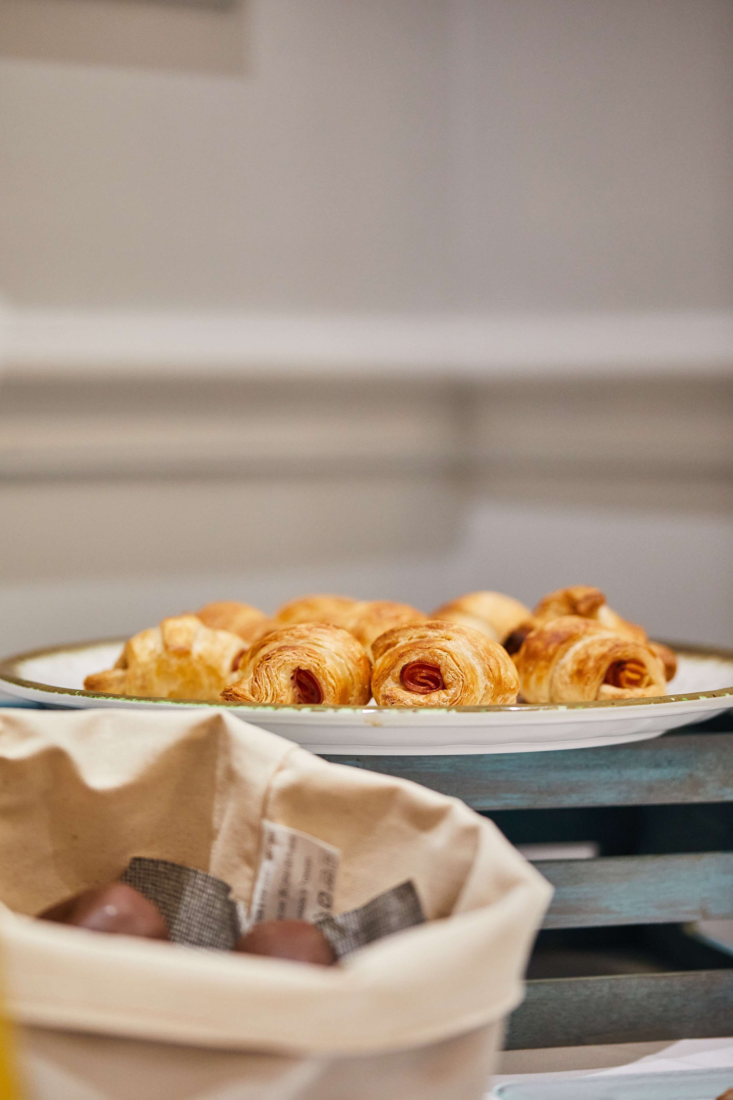 En tallrik med croissanter står på ett bord, och i förgrunden finns en korg med chokladöverdragna godisbitar.