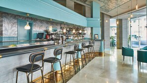 A bar area with a long counter, multiple stools, and a variety of bottles and glasses. - Hotel Silken Reino de Aragón (Zaragoza)