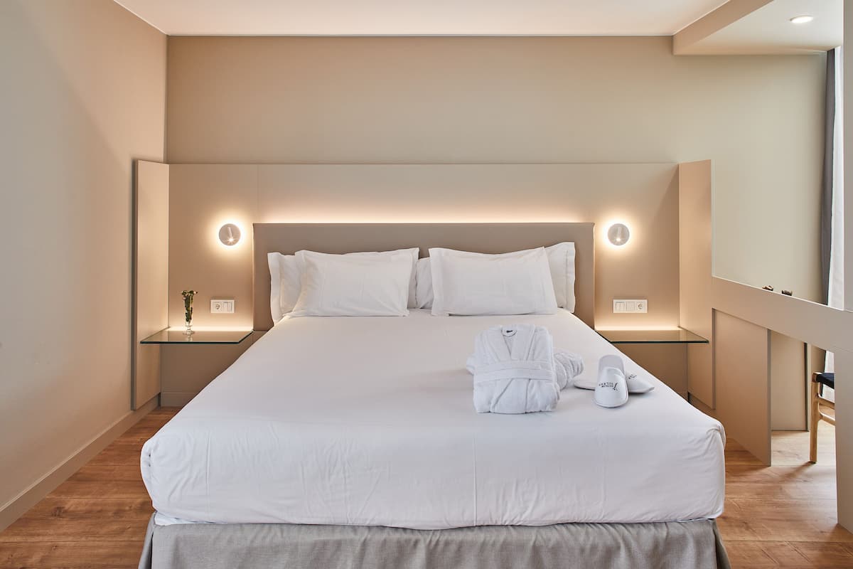 A neatly made bed with white linens, two bedside tables with lamps, and a mirror on the wall.