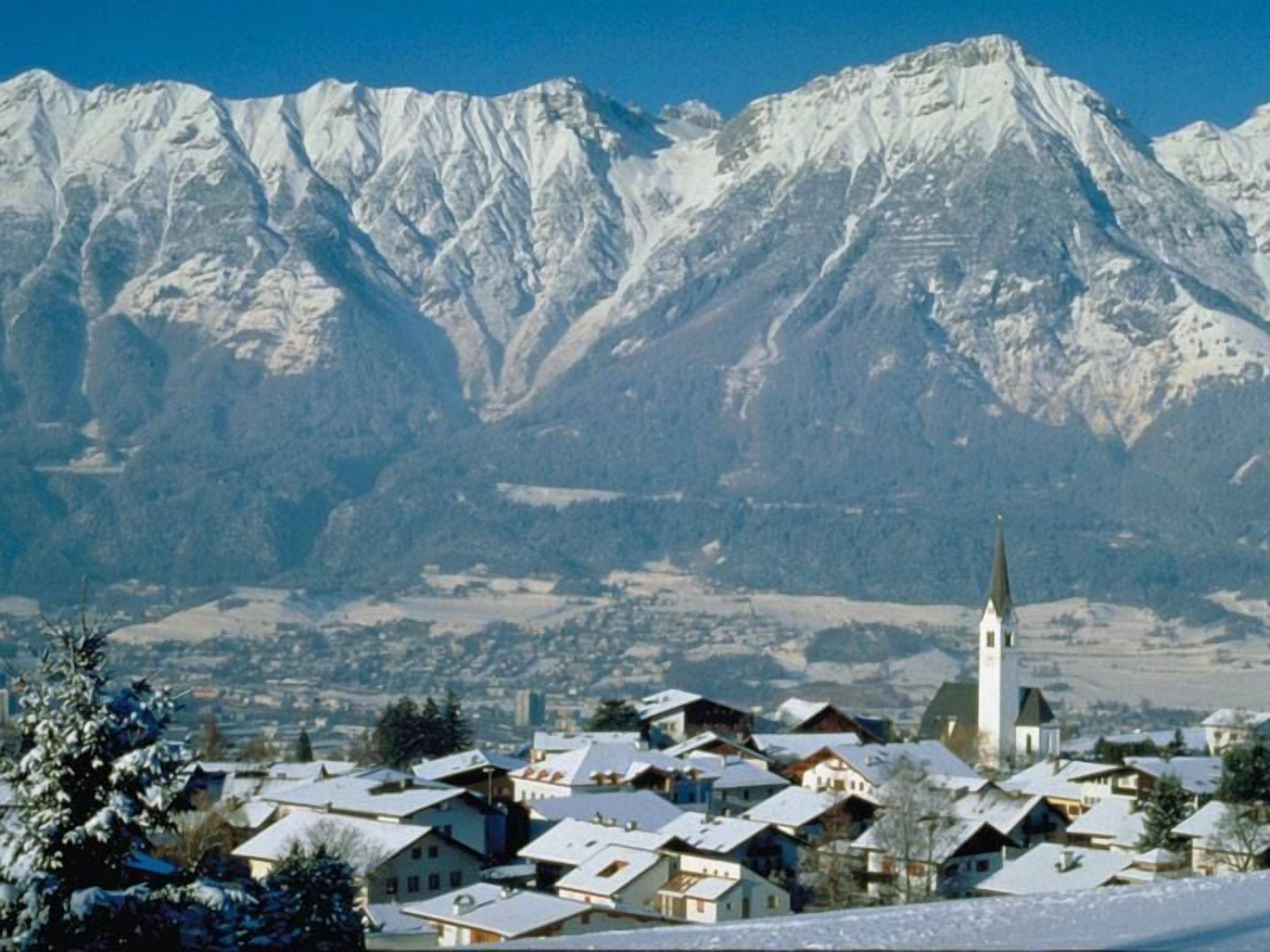 A snow-covered village with a prominent church and mountains in the background.