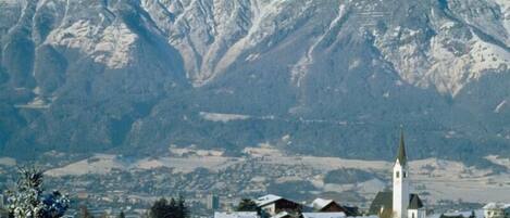 A snow-covered village with a prominent church and mountains in the background.