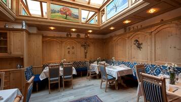 Un comedor con paredes de madera, un techo alto con tragaluces y una alfombra estampada.