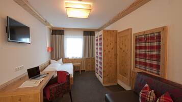 A hotel room with a bed, desk, chair, and a couch.